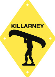 black silhouette of Person Portaging Canoe under word Killarney on bright yellow diamond-shaped background with holes in four corners, approx 17cm/6.65